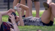 Young grils laying on the grass with thEIr mobile phones