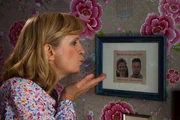 Ellis Mutter Rose (Johanna Gastdorf) hängt die gerahmte Hochzeitsanzeige an die Wand.