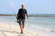 Jeremy Wade walking along deserted beach Small Hope, Andros, Bahamas.