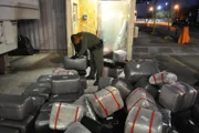 Falfurrias, Texas, USA: A Border Patrol agent organizes a pile of marijuana bundles discovered behind a false wall in a watermelon truck at Falfurrias checkpoint. (Photo Credit: NGT)