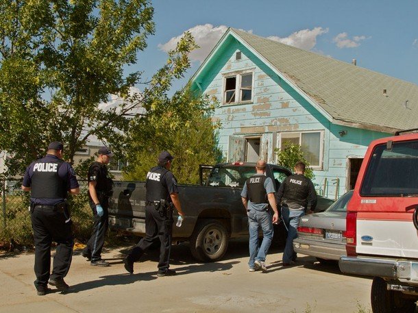 Policemen walking to a house.