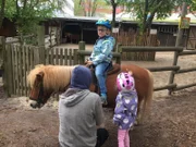 Gleicht geht es los. Jakob sitzt aufgeregt auf seinem Pony und darf gleich losreiten. Seine vierjährige Schwester Eva (re.) und sein Reitlehrer (li.) begleiten ihn.Â