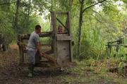 Ricky Jayroe and his son Christopher carrying a hog trap.