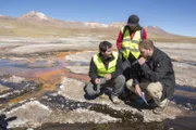 EL TATIO GEYSER FIELD, ATACAMA DESERT, CHILE, MAY 5 2017: Unknown host Josh Gates and scientist Carolina Munoz-Saez (PHD Earth & Planetary Science, currently at the University of Chile) and J.R Stok (PHD Geological Sciences, Mars Geologist, SETI Institute) discuss the silimarities between earth and Mars' geysers in El Tatio Geyser field in the Chilean Andes in the Atacama desert, the driest non-polar desert in the world, whose soil has been compared to that of Mars, owing to its otherworldly appearance, but also because bacteries and rocks at El Tatio are believed to be similar to the ones in Mars' old geysers, prompting scientist to study them in order to better understand Mars' geology and plan future missions to the red planet. El Tatio geyser field is located at 4,320 meters (14,400 feet) in the Andes Mountains of northern Chile. Its name comes from the Quechua word for oven. It is among the highest-elevation geyser fields in the world. El Tatio has over 80 active geysers, making it the largest geyser field in the southern hemisphere and the third largest in the world.