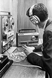In einem Zimmer werden die mit einer Wanze in einem Nebenzimmer aufgenommenen Gespräche mittels eines Transistor-Radios empfangen und von einem Tonbandgerät aufgezeichnet. Gleichzeitig können die Gespräche auch mit einem Kopfhörer mitgehürt werden. Der batteriebetriebene Sender wird in der Regel an einer versteckten Stelle im Nebenraum angebracht.