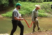 Matt Keating and Jay Marrow tethered walking by stream.