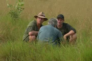 Matt and Damo squatting down listening to Charlie.