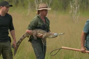 Damo holding crocodile with taped mouth. Matt looking on.