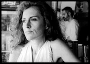 Artemis (Maria Tzivani) sitzt an der Strandbar am Tresen, während Nasos (Stavros Markalas) Getränke macht.