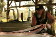 Dusty Crum and Tom Cobb pulling skin off of snake body, medium shot