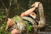 Dusty Crum wrestling snake in pond, medium shot