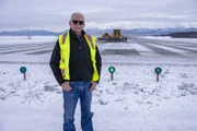 Brendon Knox in front of snow ploughs with mountains in the background