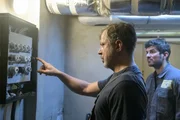 Handwerker Holger Ahrens (Sebastian Kuschmann, l.) und sein Mitarbeiter Valentin Guga (Jon Kiriac, r.) stehen im Keller von Angelika Lorenz vor einem Sicherungskasten.