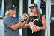 Dusty Crum and Jay Starr outside of gas station eating and playing with baby python