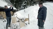 Gery Seidl versucht sich im Holzhacken, der Himmelreichbauer schaut gespannt zu.