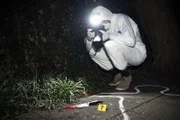 Forensics researcher photographing a blood stained knife at a murder scene