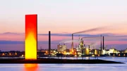 Beleuchtete Skulptur Rheinorange vor Industriepanorama in Duisburg.