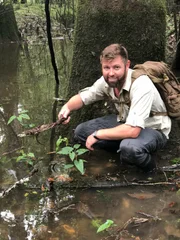 Forrest Galante Kneeling While Holding A Lizard On A Stick