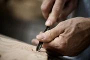 Hands of the craftsman carve a bas-relief with a gouge