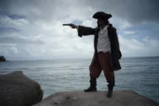 In a recreation, La Buse points his gun in the pirate paradise of the Indian Ocean.