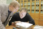 Josh Gates examines artifacts from the Dyatlov Pass Incident with historian Yuri Kuntsevich