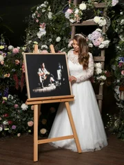 Bindi Irwin standing next to an easel with a photo of her father Steve Irwin