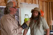 Duane Ollinger holds a jarred green substance as he and Chad Ollinger look at it.