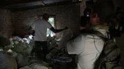 Simon Keys with cameraman in the foreground as he searches through an outside storage room for a suspected snake. (National Geographic/Dylan Theron)