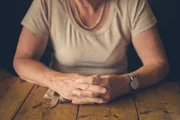A senior woman is sitting at a table in a cafe waiting for service