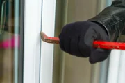 Burglar wearing black clothes and leather coat breaking in a house