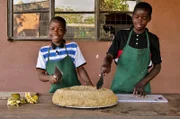 Maisbrei essen Felix und Kolleb genauso gerne wie die Schimpansen! Jeden Morgen zerschneiden sie den hartgewordenen Brei in Stücke – das Frühstück für die Schimpansen!