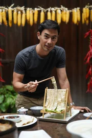 SHIPAI TOWN, JINGMEN, HUBEI, CHINA - George having a traditional tofu meal and showing the food to camera.