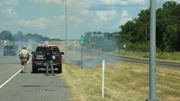 A behind the scenes shot of Texas Fish and Game Warden Benny Richards alongside the highway where a fire has started.