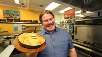 Host Casey Webb poses with the Deluxe Cheeseburger Mac at Mr. Mac's in Manchester, New Hampshire, as seen on Man v. Food, Season 4.
