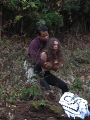 A man holding a woman down in the woods after drinking.