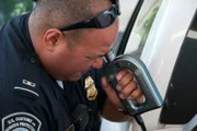 Laredo, TX: A US Customs and Border Protection official inspecting a car with a fiberscope.