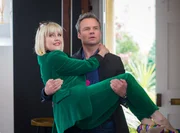 James Lacey (Jamie Glover) gratuliert Agatha Raisin (Ashley Jensen) zu ihrer bestandenen Prüfung als Privatdetektivin.