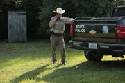 Warden Mike Boone making a phone call and leaning on a truck.