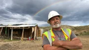 Hero shot of Jesse Goins. Arms crossed with a rainbow in the background