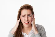 tinnitus concept - frustrated young woman having painful headache,covering closed ears,annoyed by loud noise not wanting to hear their side of story