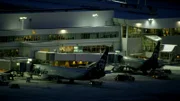 The airport terminal at night with two Alaska Airlines planes attached to passenger jetbridges