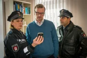 Claudia (Janette Rauch, l.) und Tarik (Serhat Cokgezen, r.) zeigen Dr. Mertin (Jörg Bundschuh, M.) ein Foto des Medikaments, das sie bei seiner Patientin gefunden haben. Dr. Mertin behauptet, dass sie dieses Medikament nicht von ihm verschrieben bekommen habe.