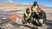 EL TATIO GEYSER FIELD, ATACAMA DESERT, CHILE, MAY 5 2017: Unknown host Josh Gates and scientist Carolina Munoz-Saez (PHD Earth & Planetary Science, currently at the University of Chile) and J.R Stok (PHD Geological Sciences, Mars Geologist, SETI Institute) discuss the silimarities between earth and Mars' geysers in El Tatio Geyser field in the Chilean Andes in the Atacama desert, the driest non-polar desert in the world, whose soil has been compared to that of Mars, owing to its otherworldly appearance, but also because bacteries and rocks at El Tatio are believed to be similar to the ones in Mars' old geysers, prompting scientist to study them in order to better understand Mars' geology and plan future missions to the red planet. El Tatio geyser field is located at 4,320 meters (14,400 feet) in the Andes Mountains of northern Chile. Its name comes from the Quechua word for oven. It is among the highest-elevation geyser fields in the world. El Tatio has over 80 active geysers, making it the largest geyser field in the southern hemisphere and the third largest in the world.