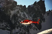 Helicopter rushing to rescue injured or lost climbers, mountaineers in Alps.