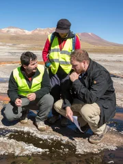 EL TATIO GEYSER FIELD, ATACAMA DESERT, CHILE, MAY 5 2017: Unknown host Josh Gates and scientist Carolina Munoz-Saez (PHD Earth & Planetary Science, currently at the University of Chile) and J.R Stok (PHD Geological Sciences, Mars Geologist, SETI Institute) discuss the silimarities between earth and Mars' geysers in El Tatio Geyser field in the Chilean Andes in the Atacama desert, the driest non-polar desert in the world, whose soil has been compared to that of Mars, owing to its otherworldly appearance, but also because bacteries and rocks at El Tatio are believed to be similar to the ones in Mars' old geysers, prompting scientist to study them in order to better understand Mars' geology and plan future missions to the red planet. El Tatio geyser field is located at 4,320 meters (14,400 feet) in the Andes Mountains of northern Chile. Its name comes from the Quechua word for oven. It is among the highest-elevation geyser fields in the world. El Tatio has over 80 active geysers, making it the largest geyser field in the southern hemisphere and the third largest in the world.