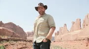 Josh Gates poses in front of stunning rock formations at Arches National Park, Utah, as seen on Travel Channel's Expedition Unknown.