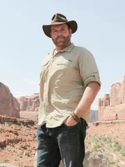 Josh Gates poses in front of stunning rock formations at Arches National Park, Utah, as seen on Travel Channel's Expedition Unknown.