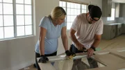 Scott helps Jasmine scrape off chipped paint from this old door, giving it more distress.