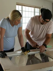 Scott helps Jasmine scrape off chipped paint from this old door, giving it more distress.