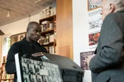 Dembe (Hisham Tawfiq, l.) nimmt in Reds Auftrag einen Koffer mit mysteriösem Inhalt in Empfang.
